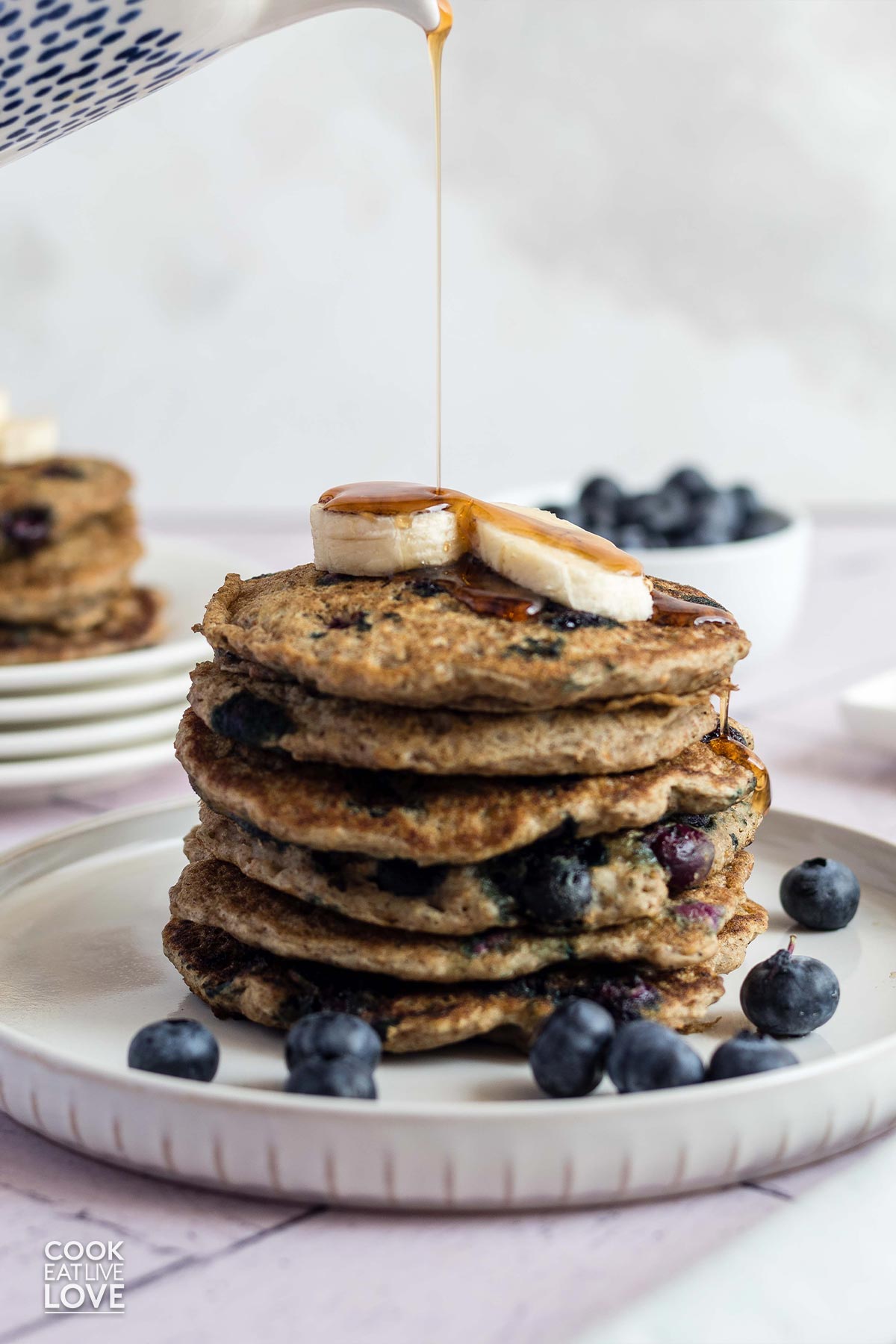 Stack of vegan blueberry pancakes on a plate with fresh blueberries.