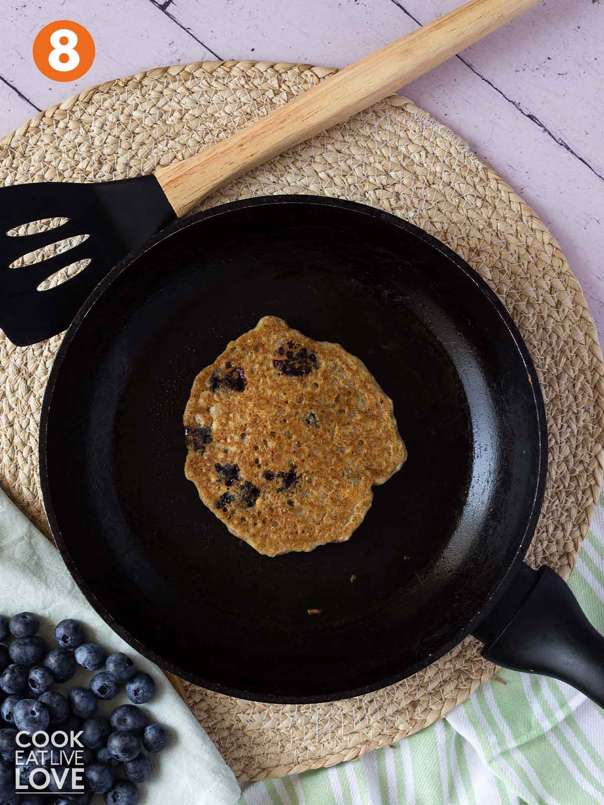 One vegan blueberry pancake flipped over to cook on the other side.
