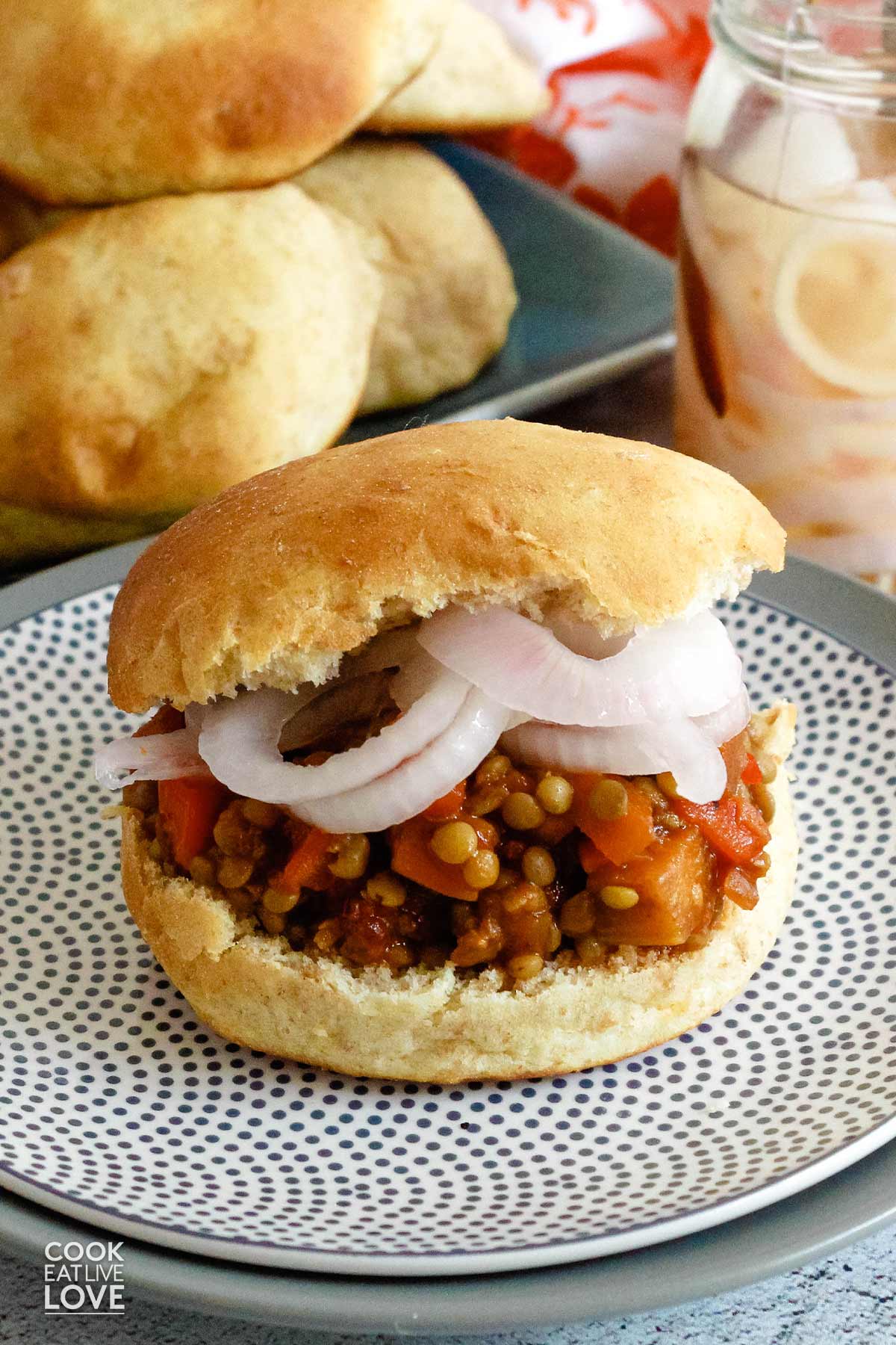 Vegan sloppy joes on a plate with stack of buns behind.