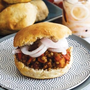Sloppy joe on a plate with onions and buns behind