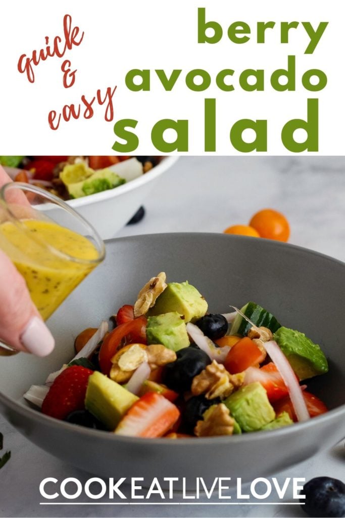 Pin for pinterest of summer berry salad in gray bowl with a hand pouring a shot glass of dressing over the salad.