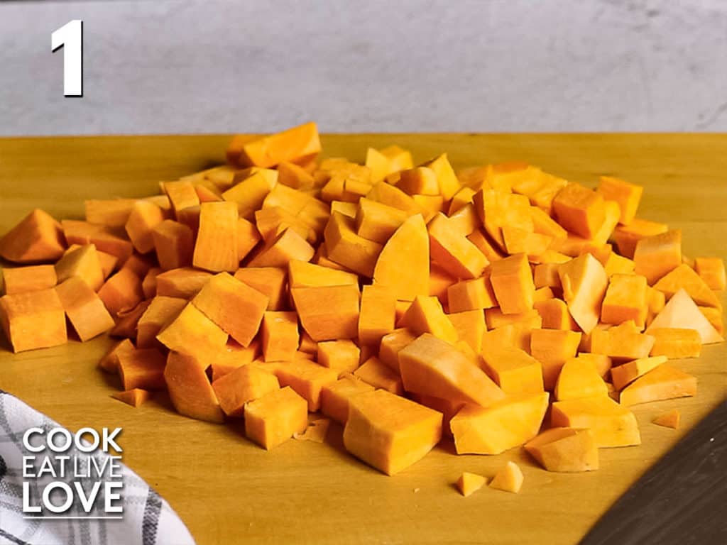 Sweet potatoes cut into cubes on a wooden cutting board.
