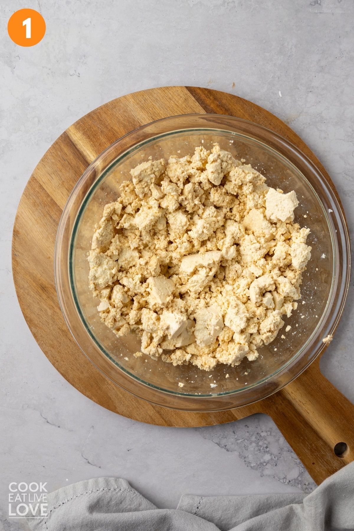 Crumbled tofu in a bowl with soy sauce added. 