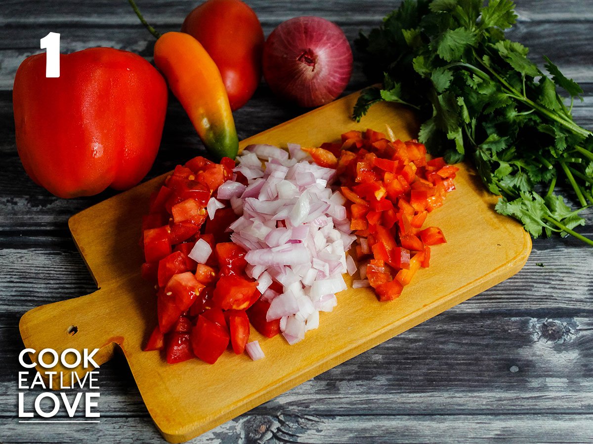 Chopped vegetables on a small wooden cutting board with whole vegetables behind it.
