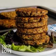 Stack of quinoa burgers on a plate with leaf lettuce.