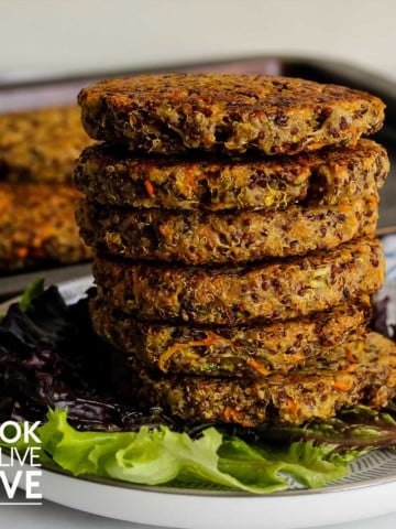 Stack of quinoa burgers on a plate with leaf lettuce.