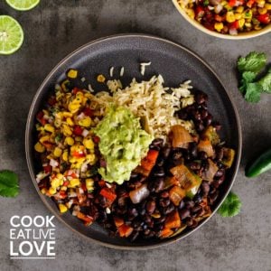 Brown plate on table with black beans and rice topped with guacamole