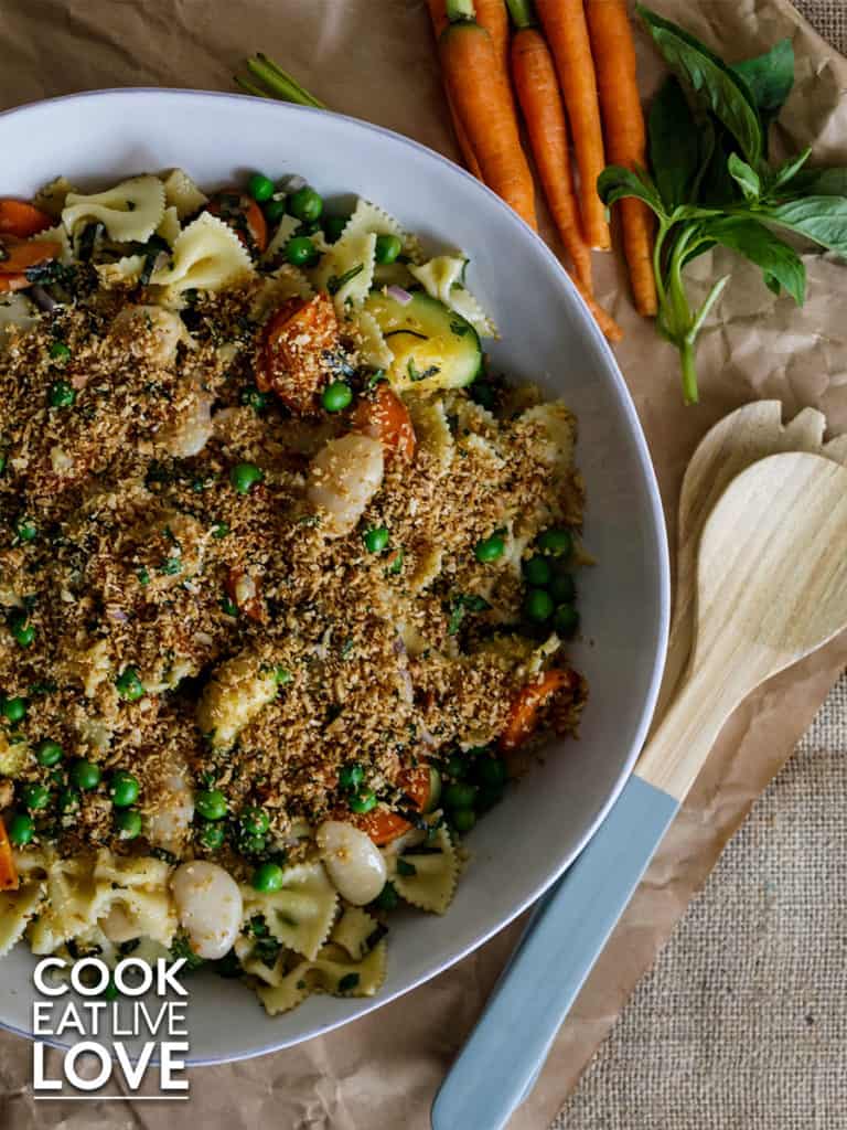 Large bowl of pasta with breadcrumb topping and serving spoons