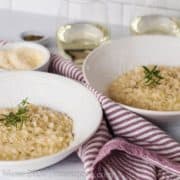 Bowls of risotto on white background with red and white striped towel in between.