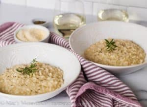 Bowls of risotto on white background with red and white striped towel in between.