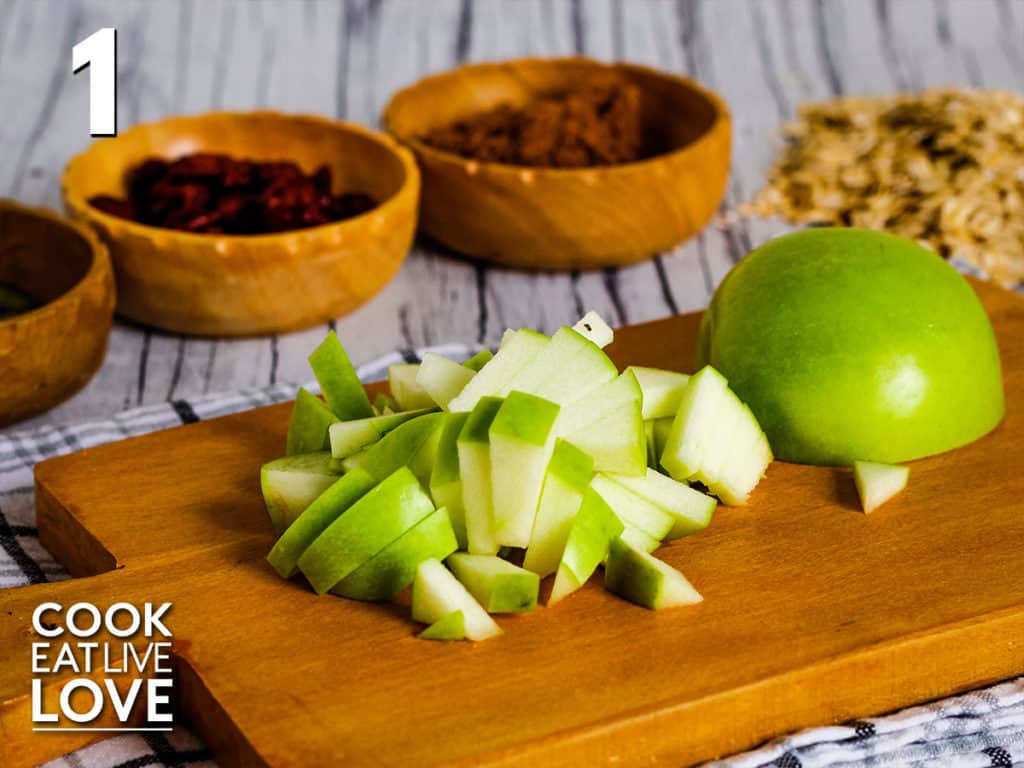 Chopped apple on a cutting board with other ingredients in the background to show the correct size of the apple.