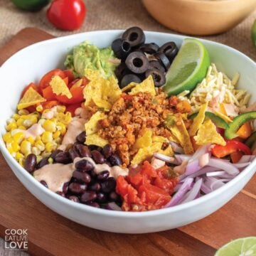 A vegan taco salad on the a wooden cutting board.