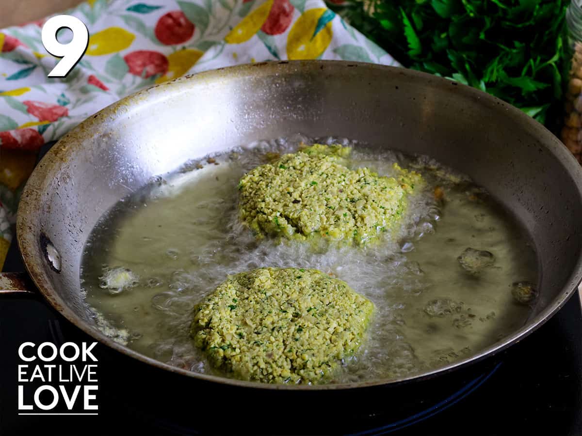 Frying pan with oil and two falafel cooking.