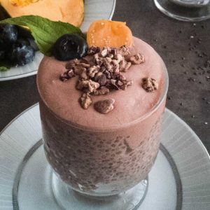 Lucuma powder chia pudding served up a in glass topped with cacao nibs and fresh mint.