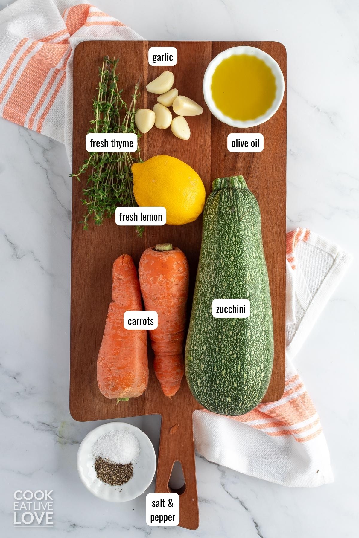 Ingredients to make roasted zucchini and carrots on a wooden cutting board on the table.