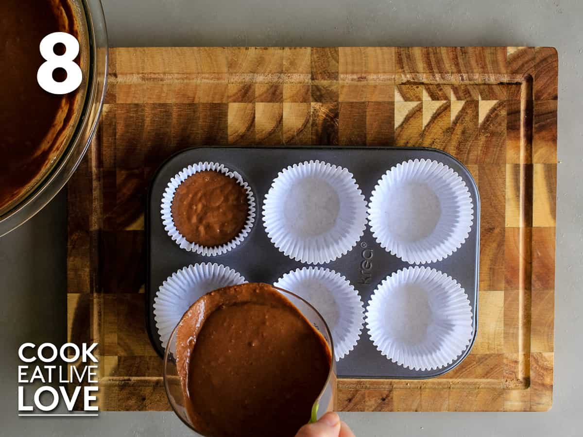 Pouring the batter into a lined cupcake tray.