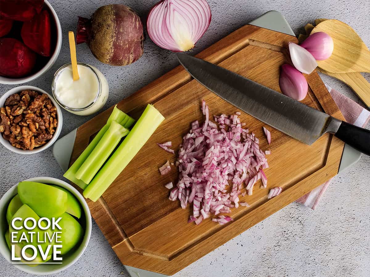 overhead view of diced onions on cutting board with other ingredients for beet and apple salad