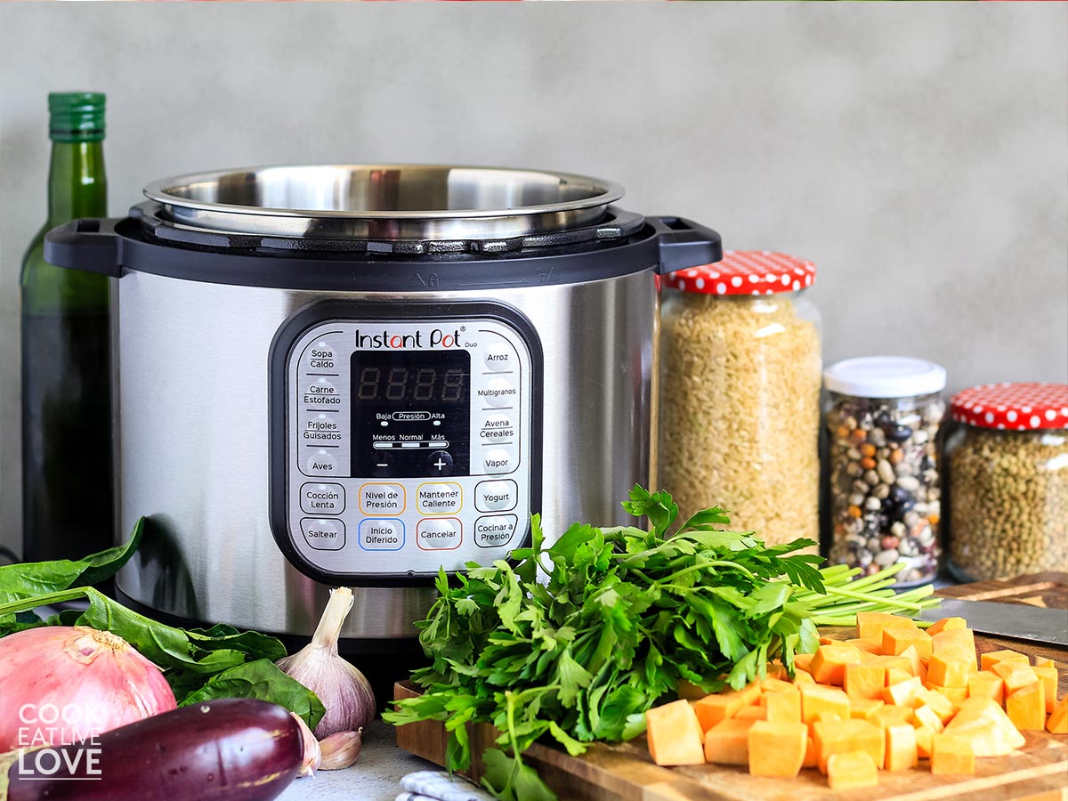 Instant pot on counter with vegetables and ingredients around it.