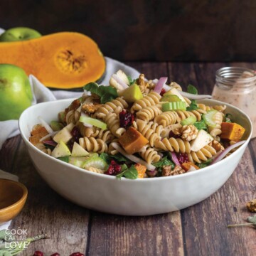 Fall pasta salad in white rectangle bowl with wooden serving spoons.