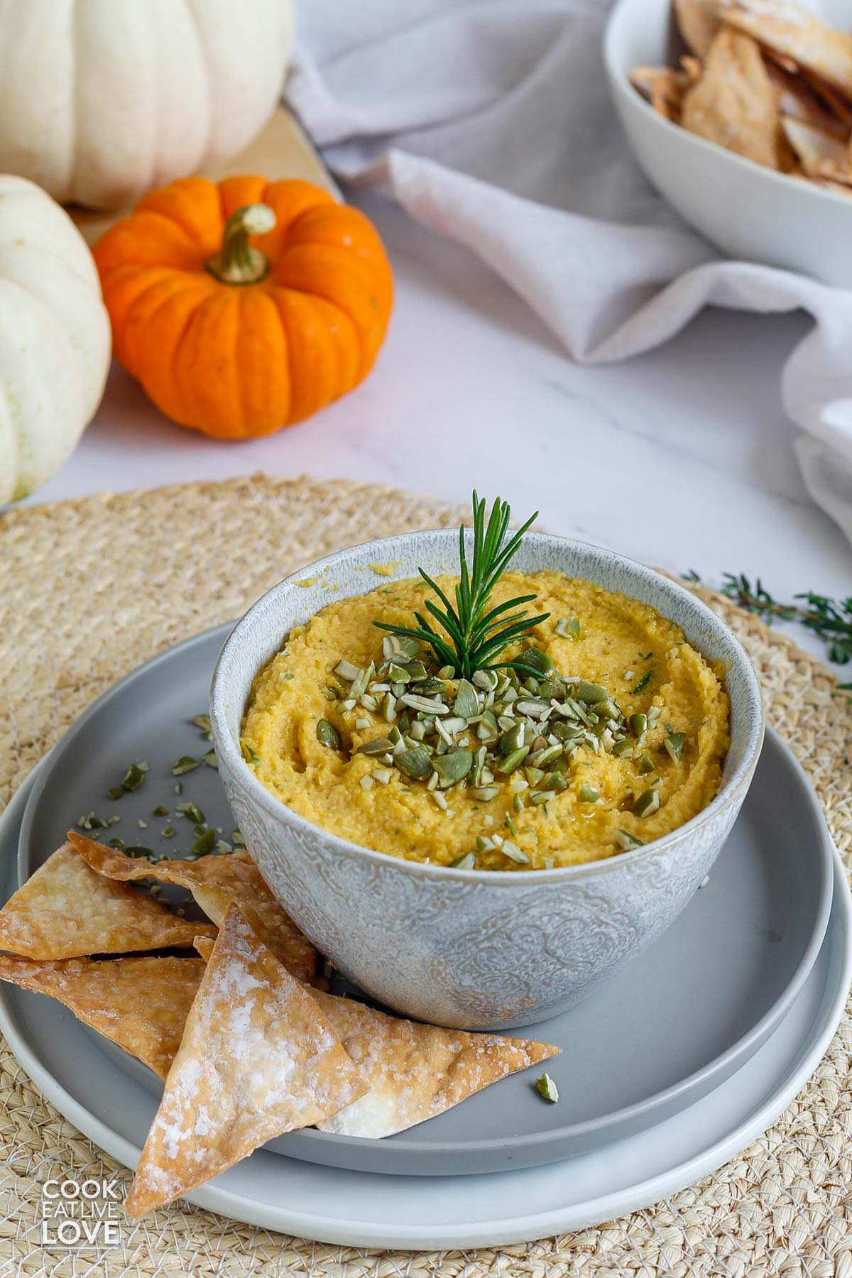 Savory pumpkin dip in a bowl on a plate with wonton chips.