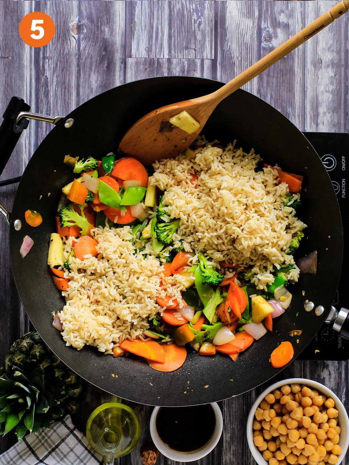 Rice is added to wok with cooked vegetables.