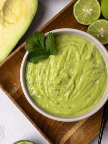 Avocado sauce in a bowl topped with fresh cilantro.