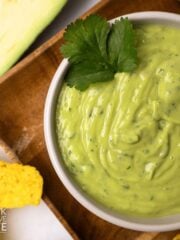 Avocado sauce in a bowl with cilantro and chips.