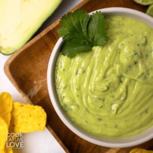 Avocado sauce in a bowl with cilantro and chips.
