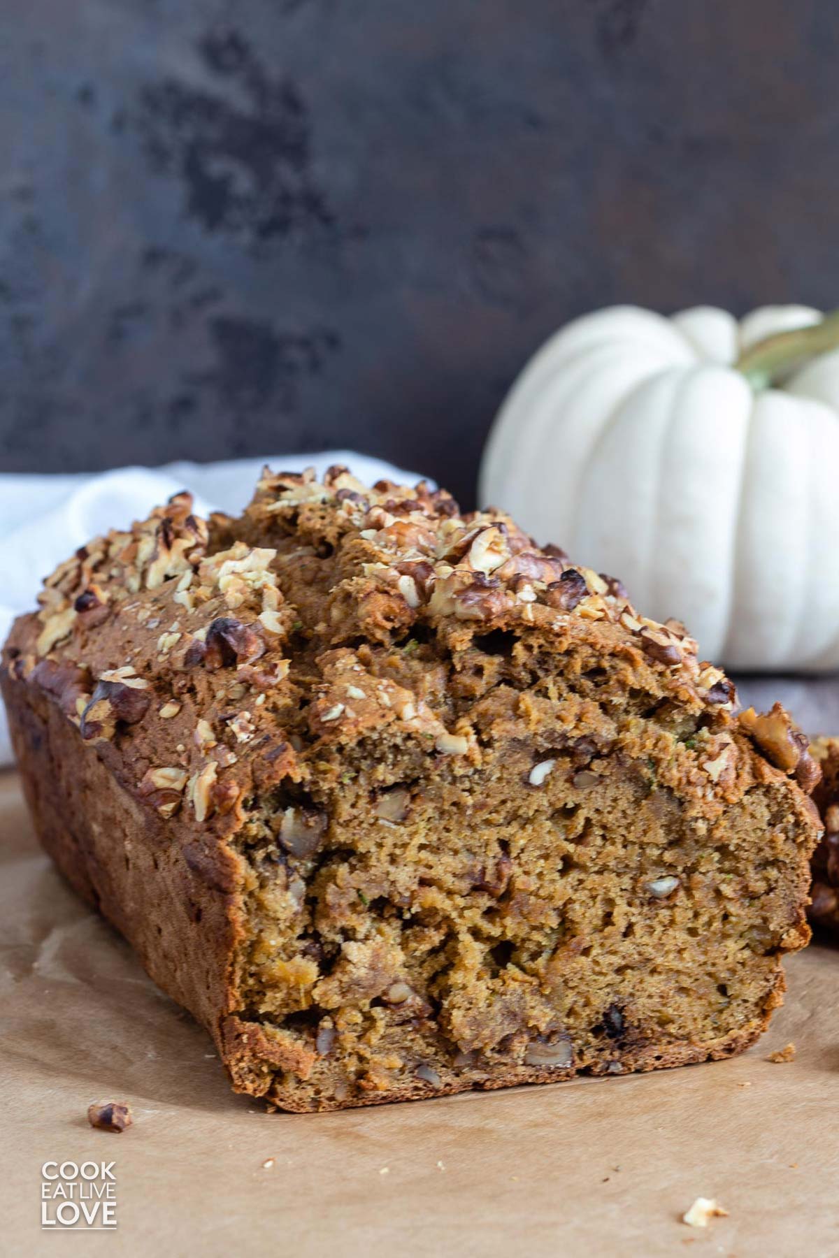 Loaf of pumpkin zucchini bread on the table with a slice cut to show the inside.