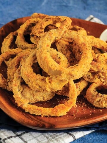 Vegan baked onion rings on a plate as a side dish to a sandwich.