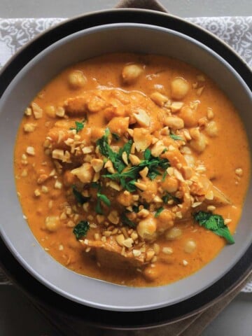 Bowl of vegan massaman curry served up with chopped peantus.