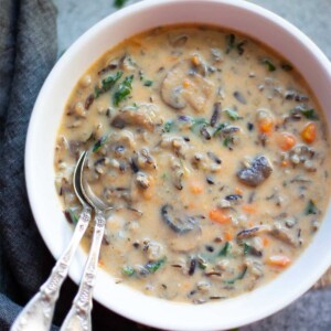 Bowl of creamy wild rice soup with spoons off to the side in the bowl of soup.