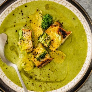 Creamy broccoli soup in a bowl with croutons and herbs.