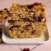 Vegan granola bars are piled up on small square plate.