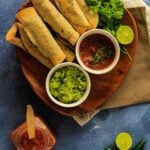 Taquitos on a plate with salsa and guacamole