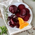Beets on a plate garnished with orange slices and fresh herbs