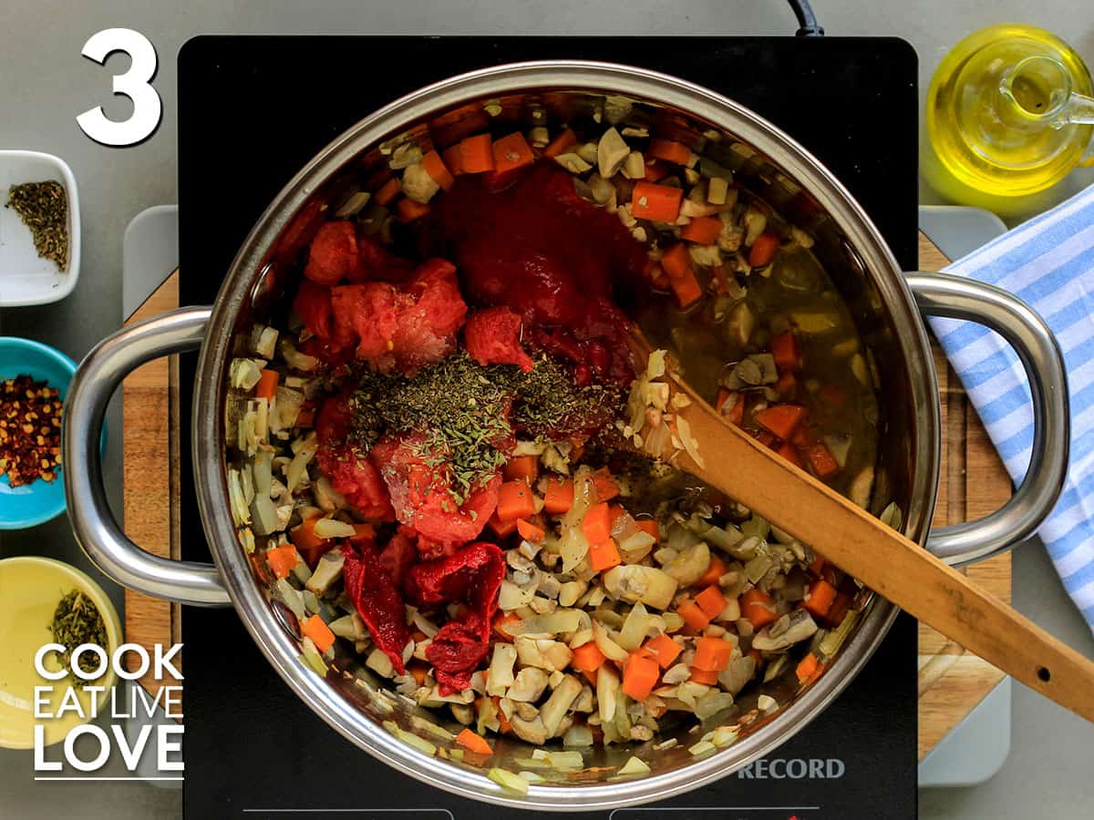 Seasonings and tomatoes added to cooked vegetables in skillet