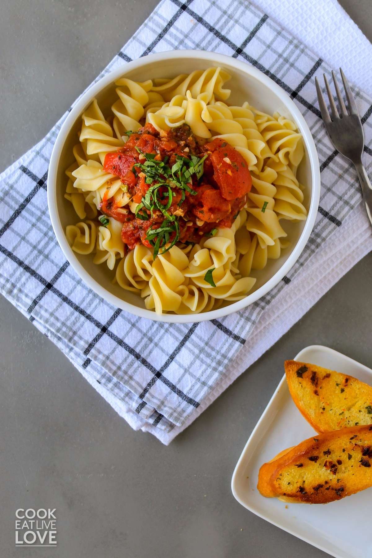 A bowl of pasta on the table topped with hearty marinara sauce.