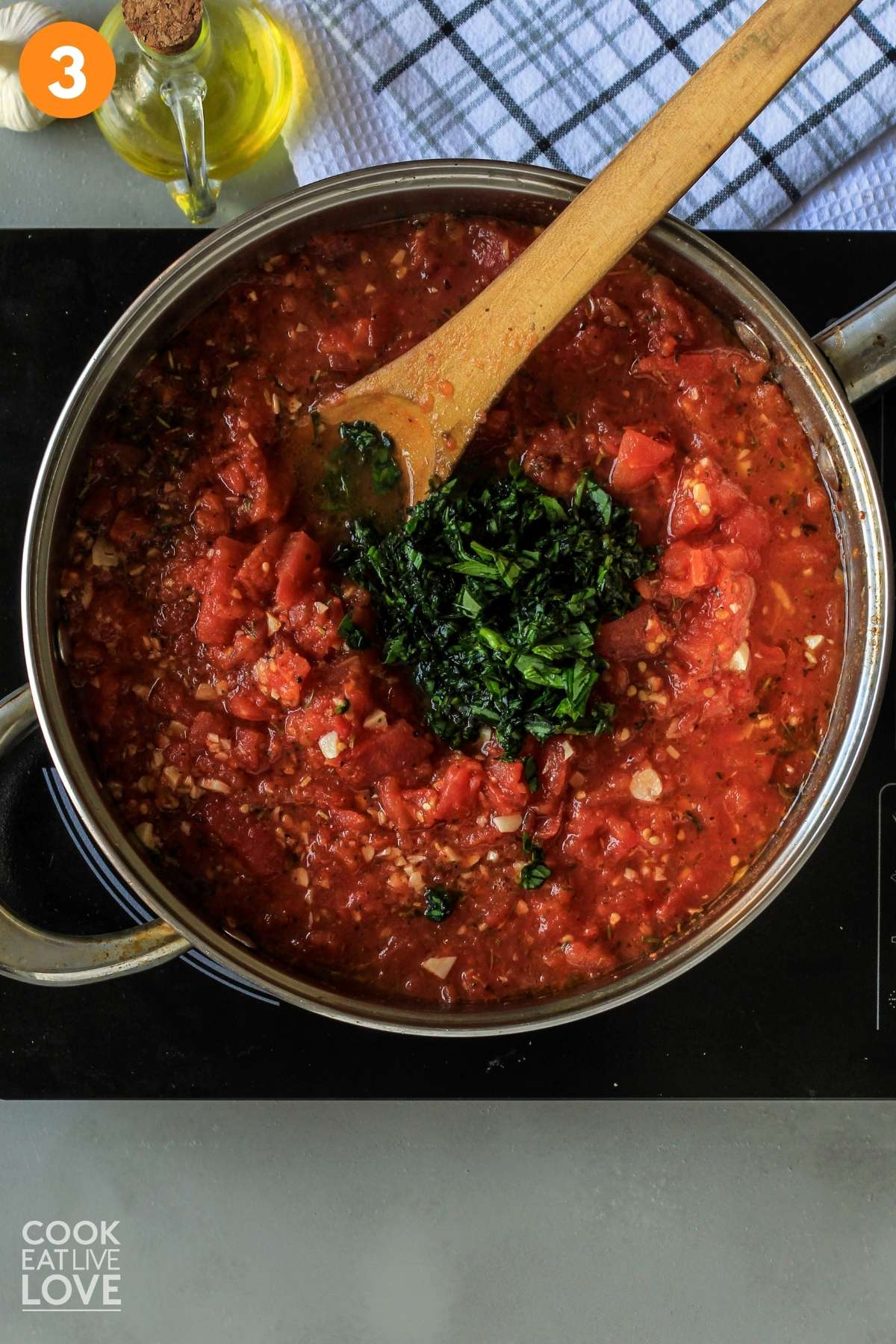 Basil is added to the cooked marinara sauce.