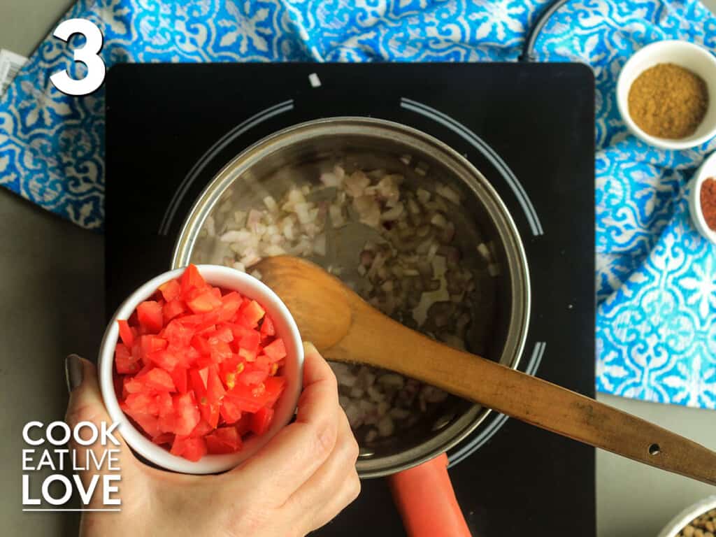 Adding tomatoes to the pan of sauteed onions