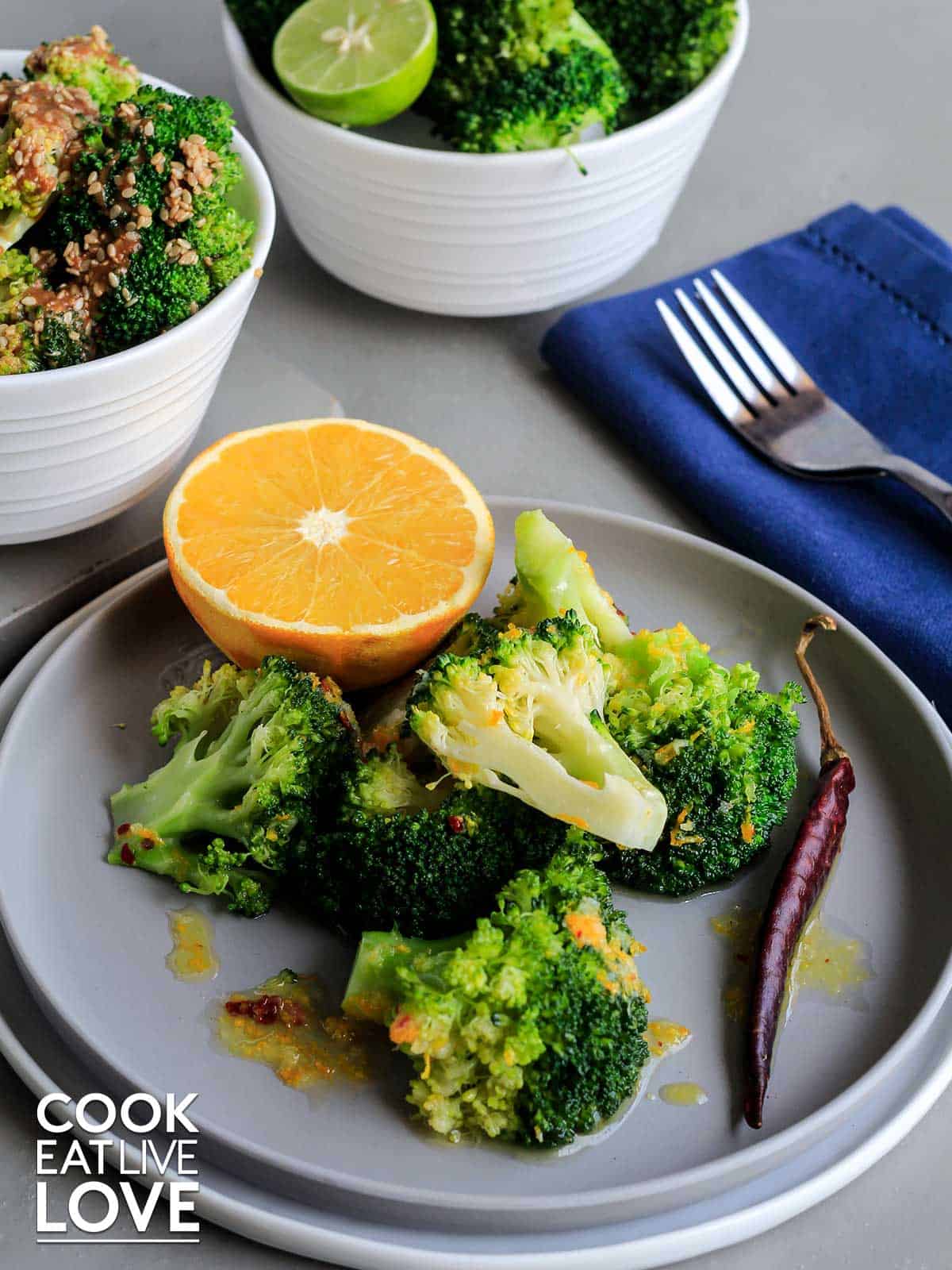 Broccoli on a plate with orange and chile garnish.