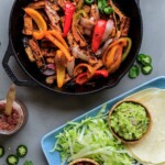 Tofu fajitas cooked in cast iron skillet with toppings and tortillas