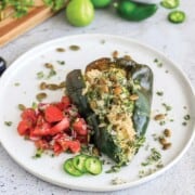 Vegetarian stuffed poblano pepper served up on a plate with pico de gallo