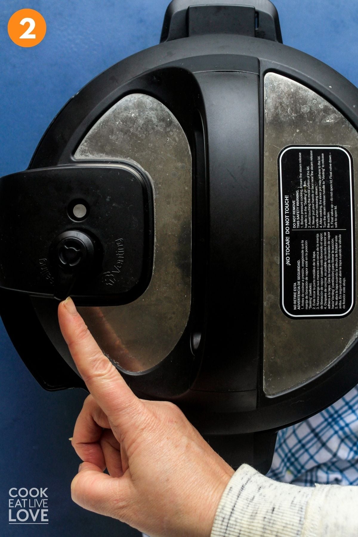 Instant pot lid closed and a finger pointing the pressure valve. 