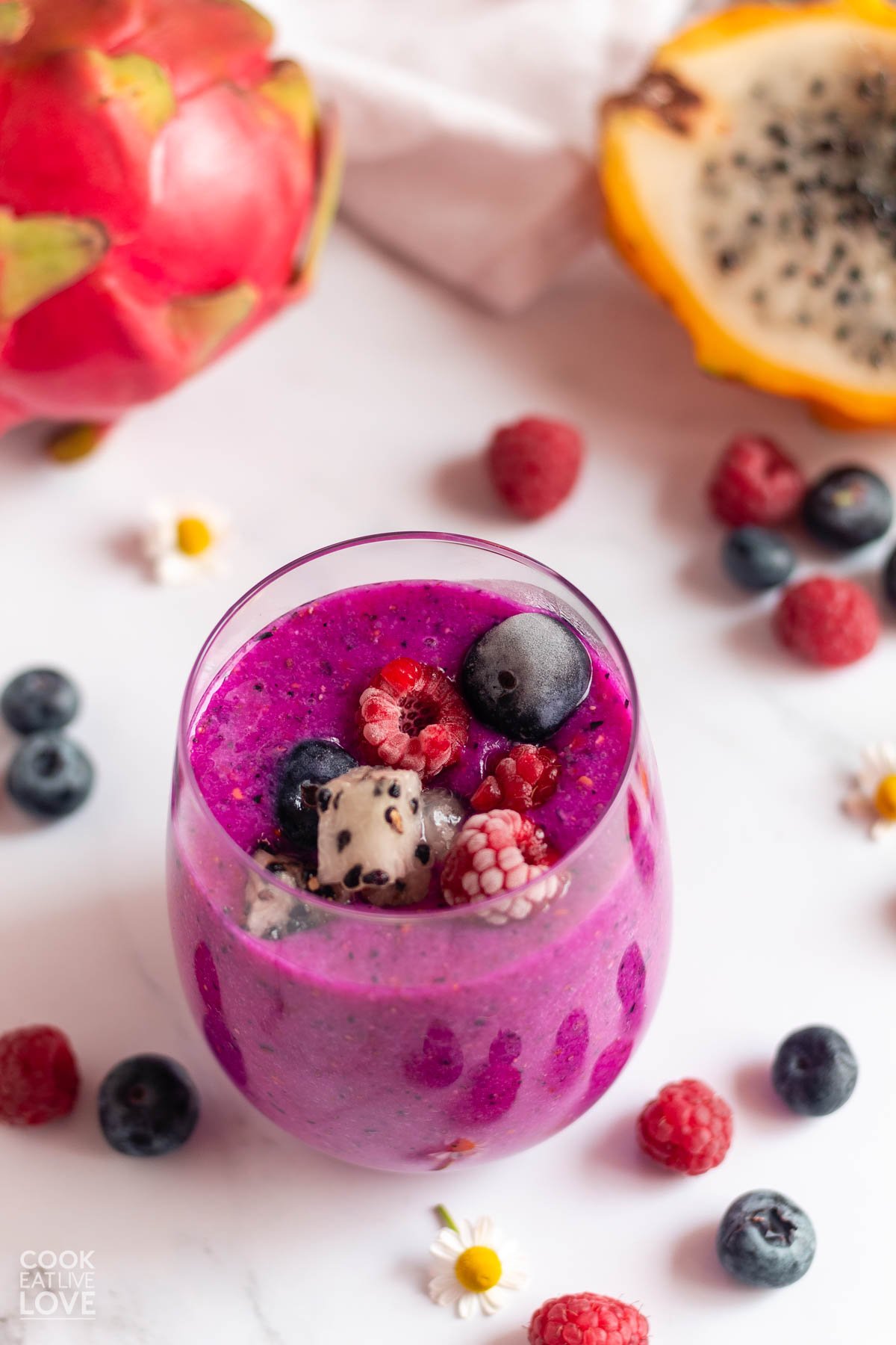 Purple summer smoothie in a glass with berries on top.