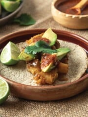 Potato tacos on a plate with limes and salsa