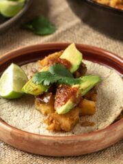 Potato taco on a plate with salsa and avocado.