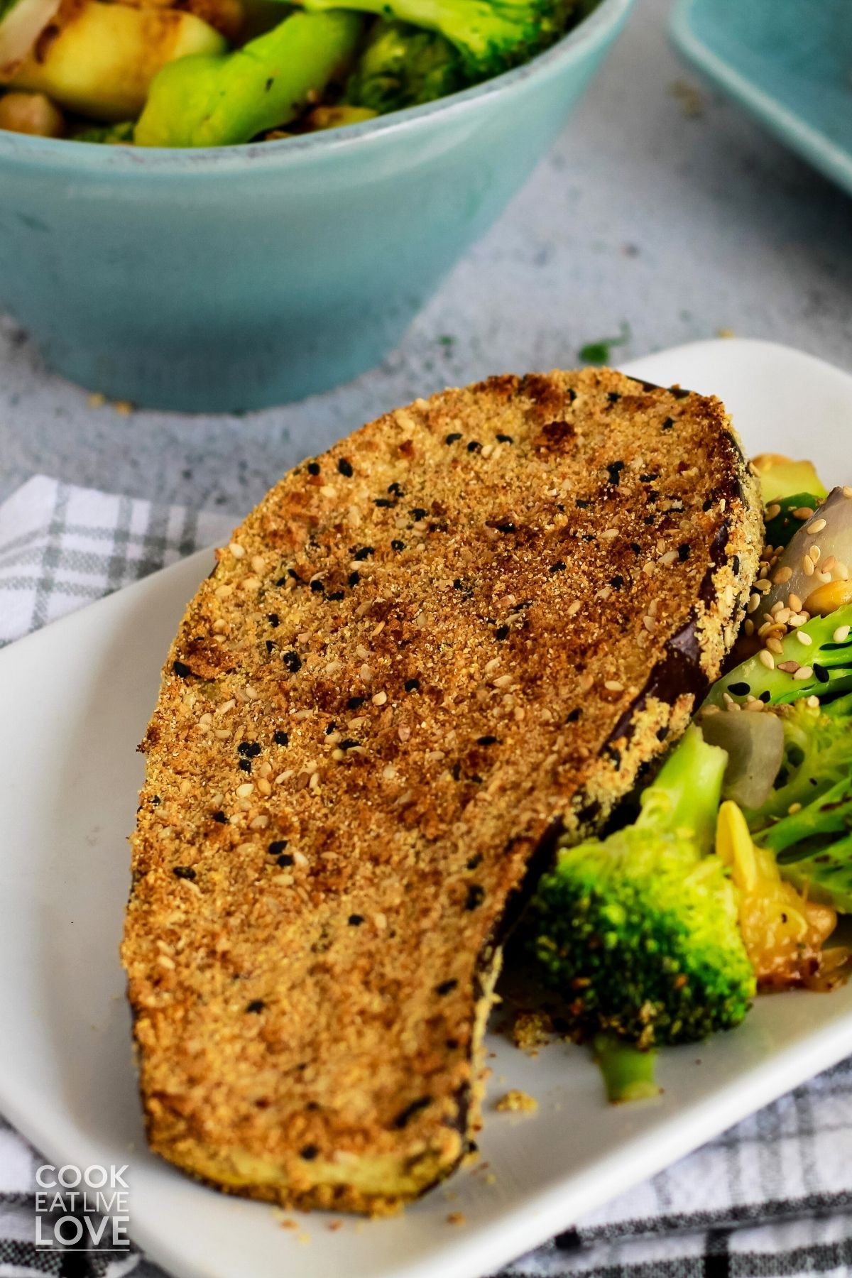 Crispy eggplant on a white plate with broccoli.