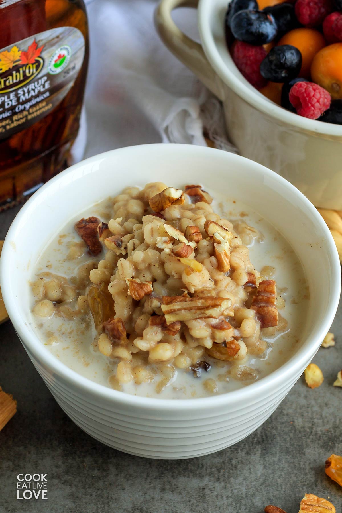 A bowl of barley porridge on the table topped with nuts.