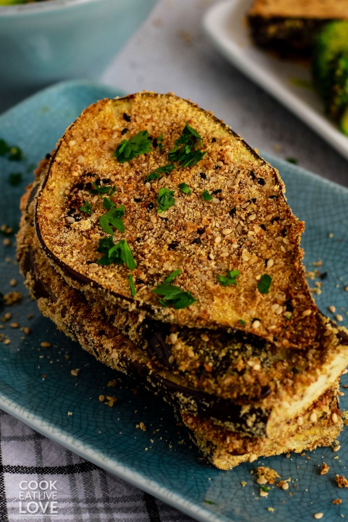 Crispy breaded eggplant cutlets stacked on a blue rectangle plate. 
